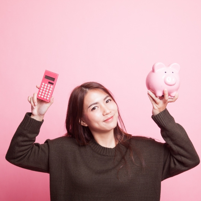 a woman holding a piggy back and calculator