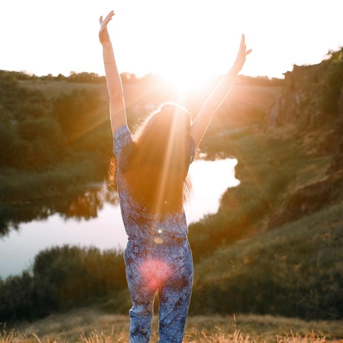 girl stands on a mountain and looks at the sunset