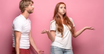 The conflict of couple - woman threatening and showing strength on pink background