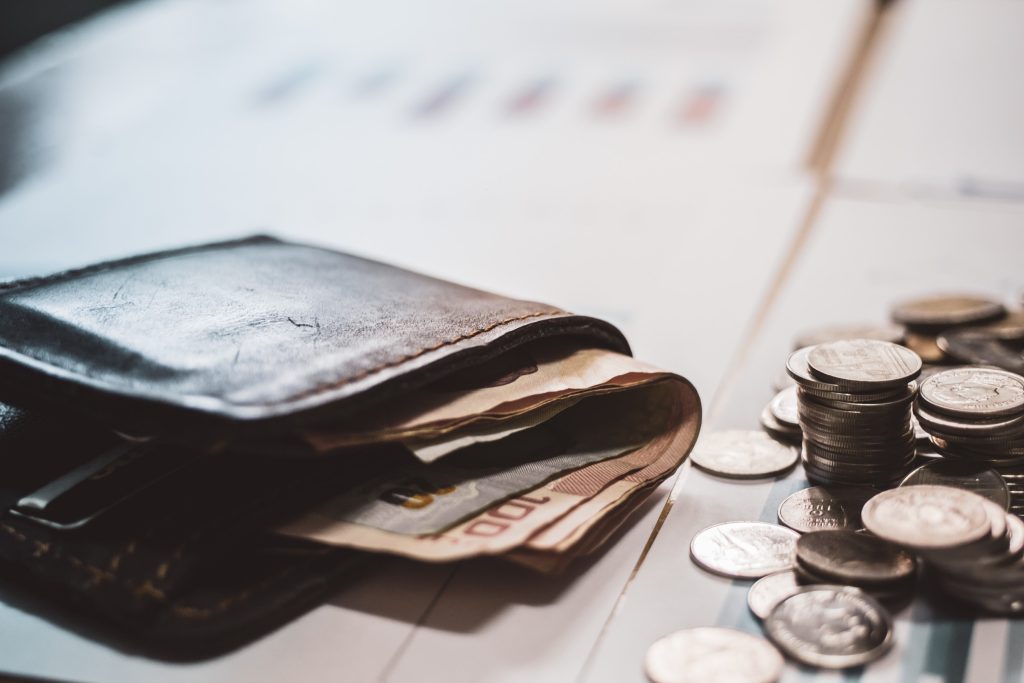 Silver coins and cash placed in piles on desk with light sunset