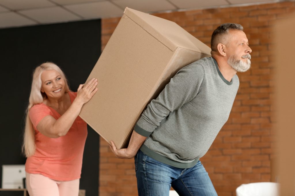 Mature couple with big moving box at new home