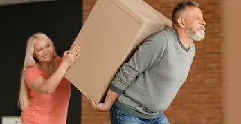 Mature couple with big moving box at new home