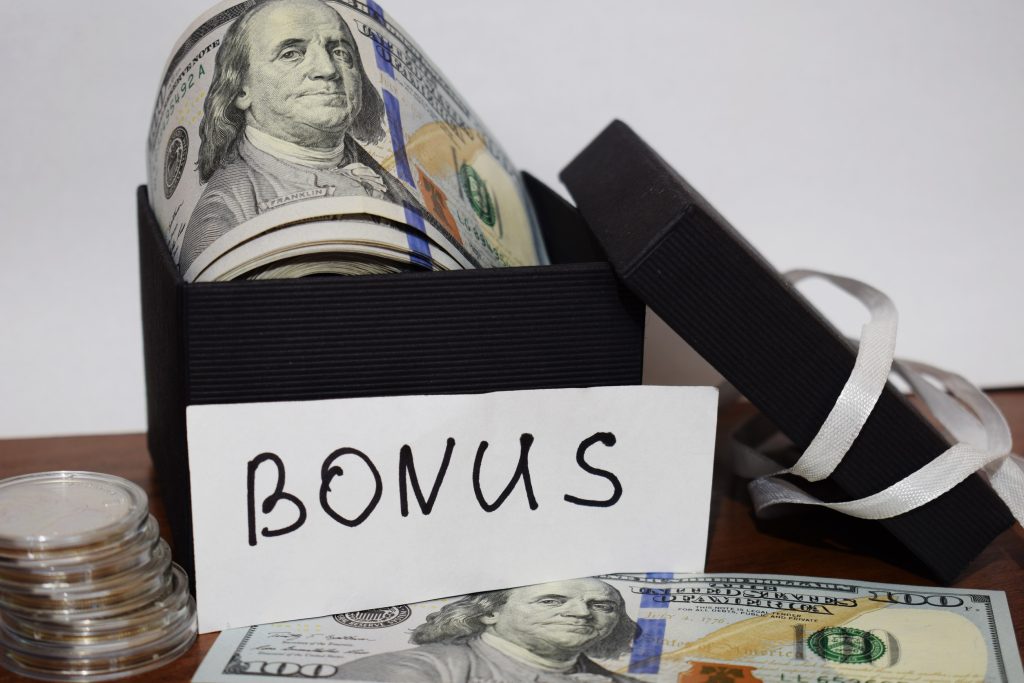 Gift package with dollars on the table on a white background, the inscription Bonus