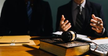 Business and lawyers discussing contract papers with brass scale