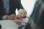 Real estate agent and customer signing contract to buy house