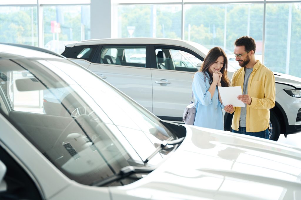 Photo of happy couple in car showroom